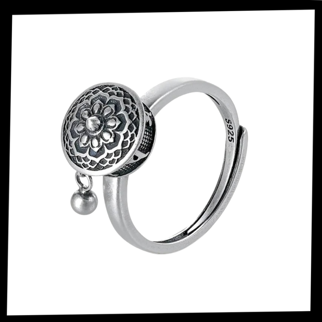 Anel feminino Freedx com mantra budista rotativo, design elegante em prata, destaque para detalhes delicados na imagem.
